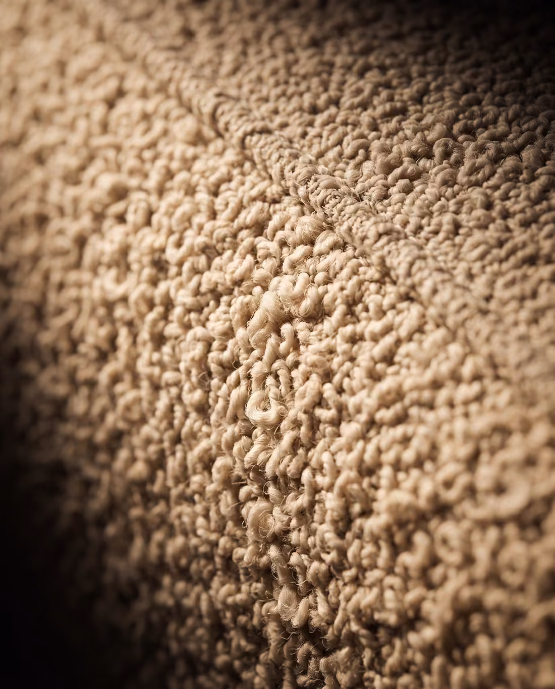 Close-up of the oatmeal boucle upholstery, showing its dense looped texture and a welted seam.